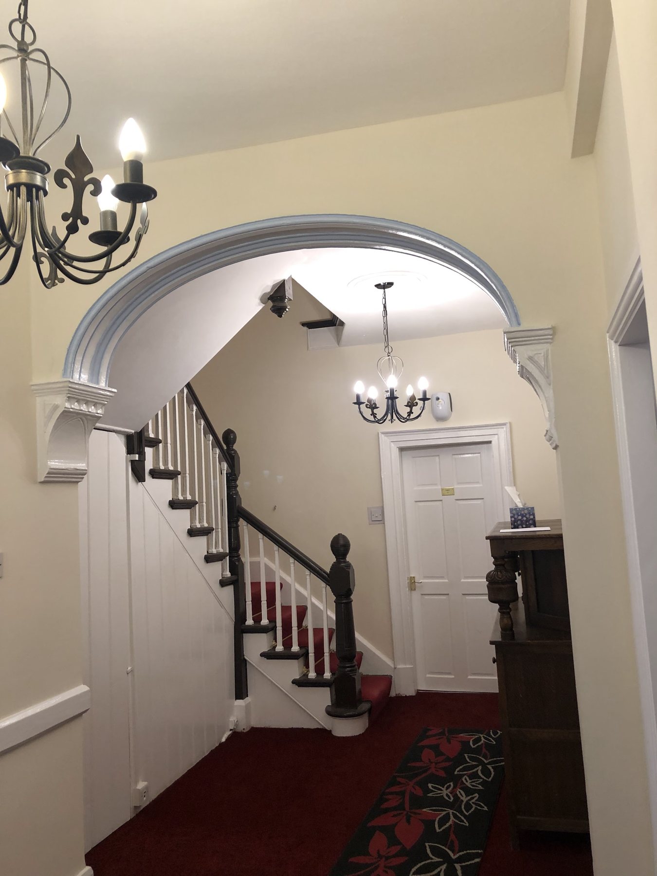 The hallway and staircase inside The White House, with a chandelier and red stair carpet