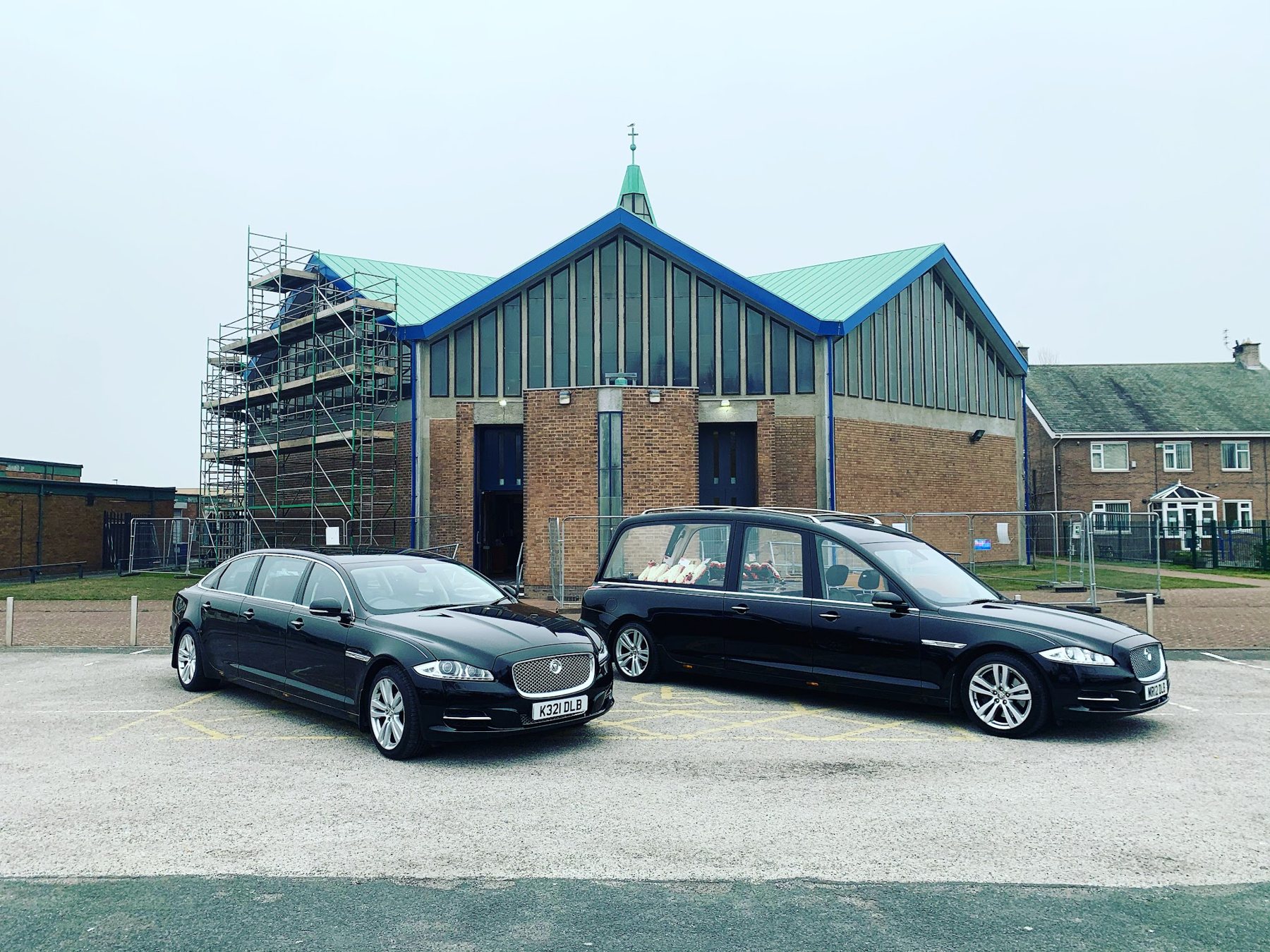 Two black limousines parked outside a chapel